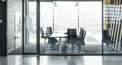 A modern, empty conference room with a long table, black chairs, glass walls, and large windows letting in natural light—ideal for Chicago lawyers meeting to discuss intellectual property law or provide litigation support.