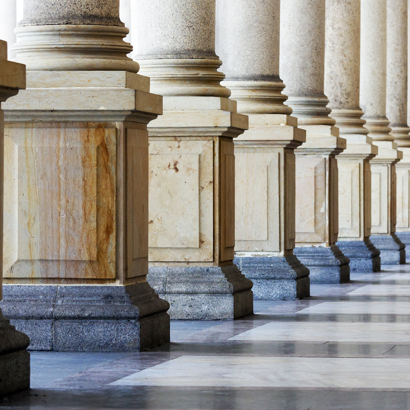 A row of large stone columns with square bases, set on a marble floor in a classical architectural style, evokes the tradition and authority often found in Chicago lawyers' offices.