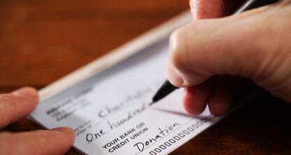 A person writes a check with the word "donation" marked in the memo field, seeking advice from Chicago lawyers about proper charitable giving documentation.