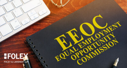 A black spiral notebook labeled "EEOC Equal Employment Opportunity Commission" sits on a desk beside a keyboard, glasses, and a pen—an essential workspace accessory for Chicago lawyers navigating intellectual property law.