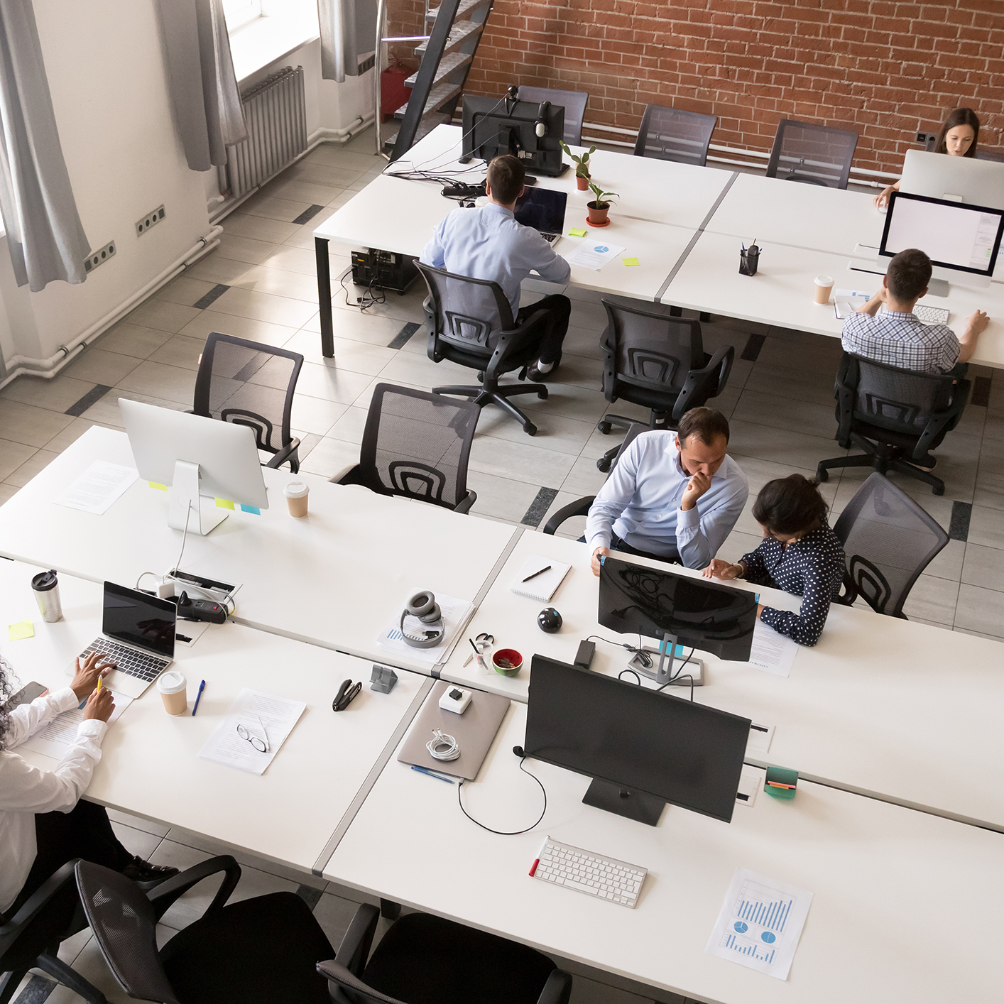 Modern open-plan law offices with chicago lawyers working at desks, using computers and paperwork, set against brick walls and large windows.