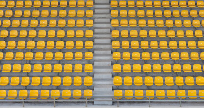 Rows of empty yellow stadium seats with a central aisle running vertically between them, reminiscent of the orderly precision often seen in litigation support provided by top lawyers in Chicago.