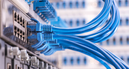 Close-up of several blue Ethernet cables plugged into a network switch, with blurred network hardware visible in the background of a Chicago lawyers’ corporate law office.