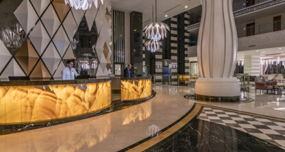 Elegant lobby with modern geometric decor, marble floors, illuminated front desk, and staff ready to assist—perfect for a corporate law office seeking a refined and professional atmosphere.