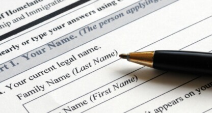 A black pen rests on a government immigration form requesting the applicant's current legal name, family name, and given name—items often reviewed by Chicago lawyers offering litigation support.