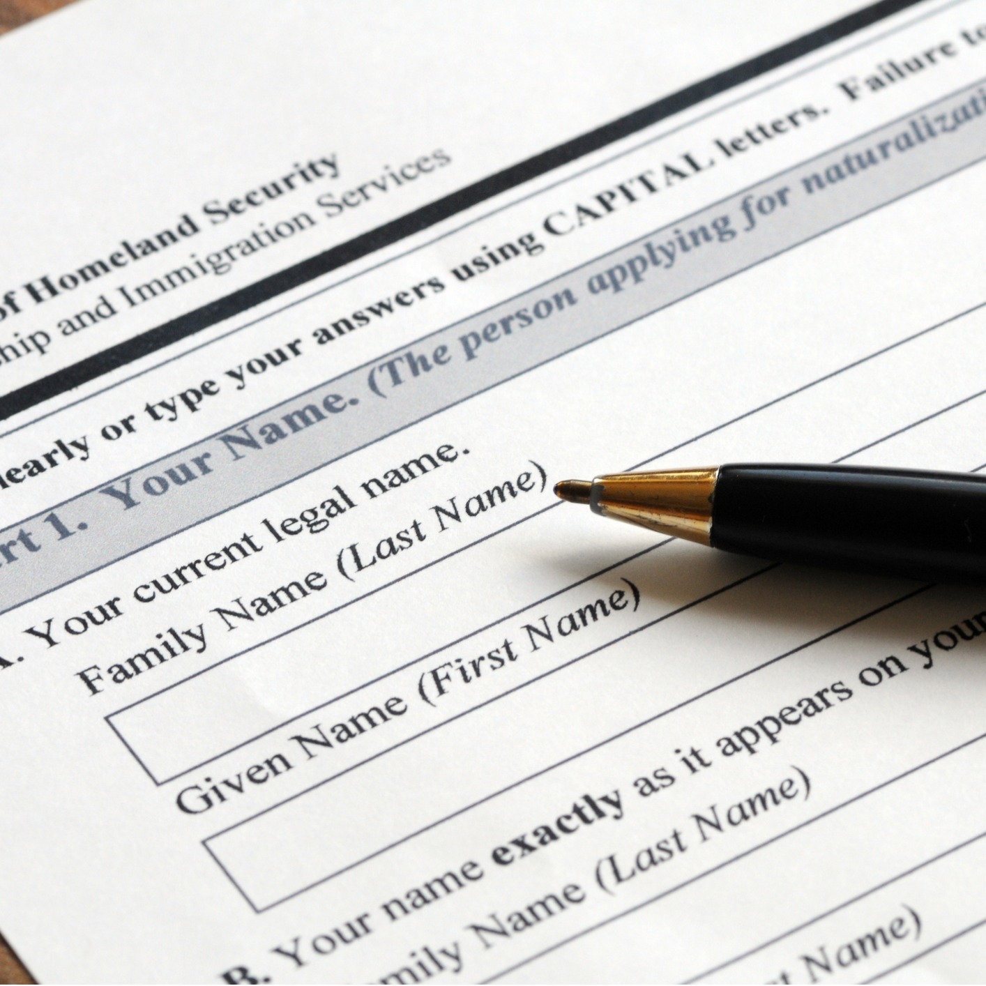 A black pen rests on a government immigration form requesting the applicant's current legal name, family name, and given name—items often reviewed by Chicago lawyers offering litigation support.