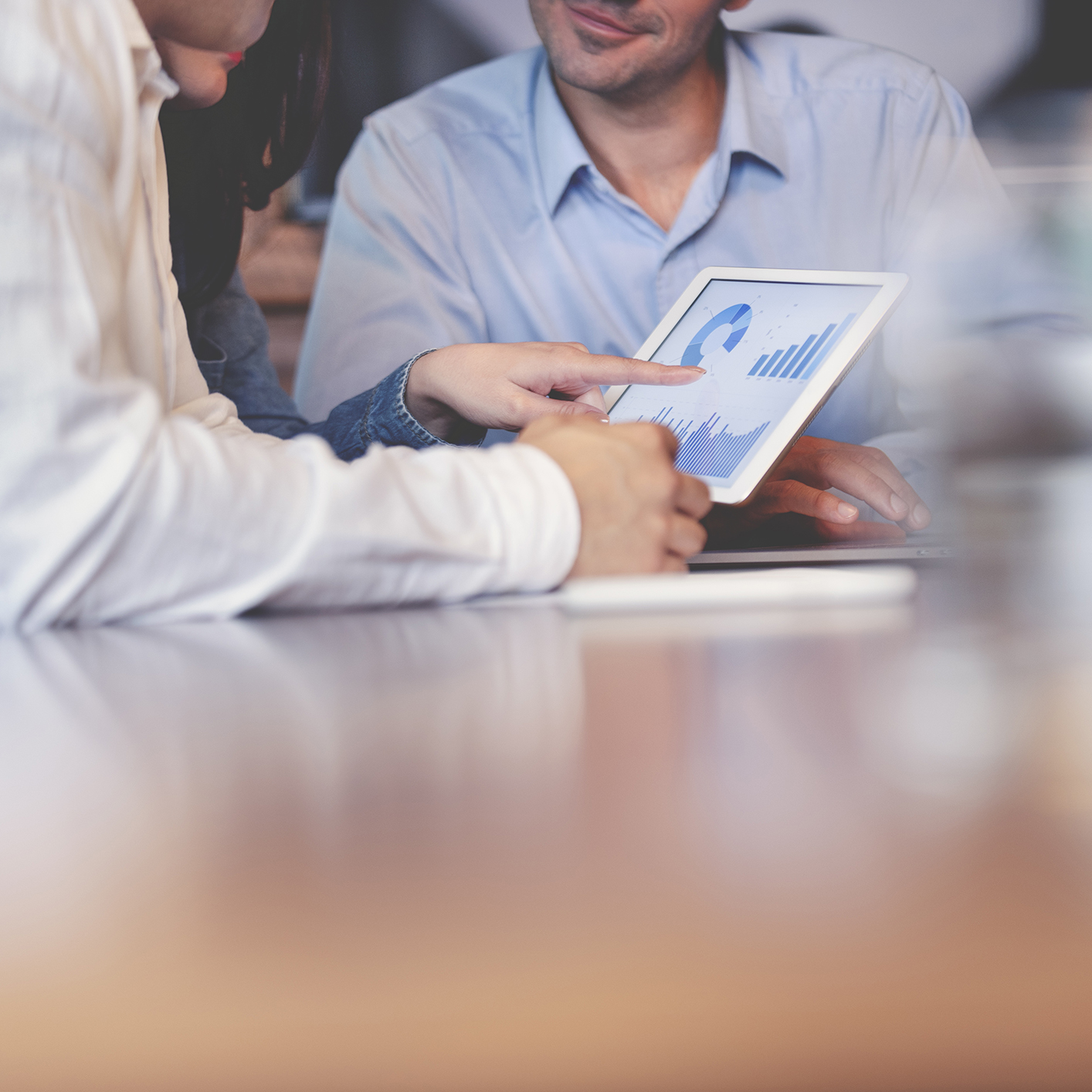 Two people sit at a table, one pointing at a tablet displaying charts and graphs related to litigation support, while the other watches attentively.