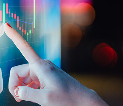A hand with red nail polish touches a transparent screen displaying colorful financial graphs and candlestick charts—ideal for lawyers in Chicago seeking advanced litigation support against a dark, blurred background.