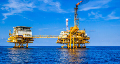 Una plataforma petrolífera en alta mar con una chimenea de quema que emite humo, situada en el océano bajo un cielo azul y despejado: una imagen a la que suelen hacer referencia los equipos y abogados de los bufetes especializados en derecho mercantil de Chicago que se ocupan de la compleja normativa marítima.