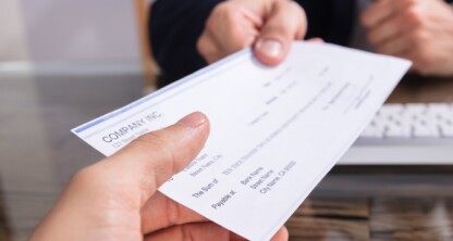 A person hands a check to another across a desk in a professional office setting, highlighting the financial transactions often seen in law offices providing litigation support.
