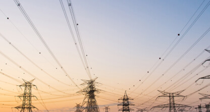 Multiple high-voltage power transmission towers and wires stretch across a dry, open landscape at sunset, evoking the interconnected strength found in leading law offices and lawyers in Chicago.