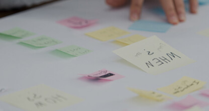 Hands arranging various colored sticky notes with handwritten text on a white surface, suggesting a brainstorming or planning session by Chicago lawyers specializing in intellectual property law.