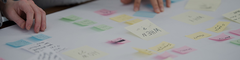 Hands arranging various colored sticky notes with handwritten text on a white surface, suggesting a brainstorming or planning session by Chicago lawyers specializing in intellectual property law.