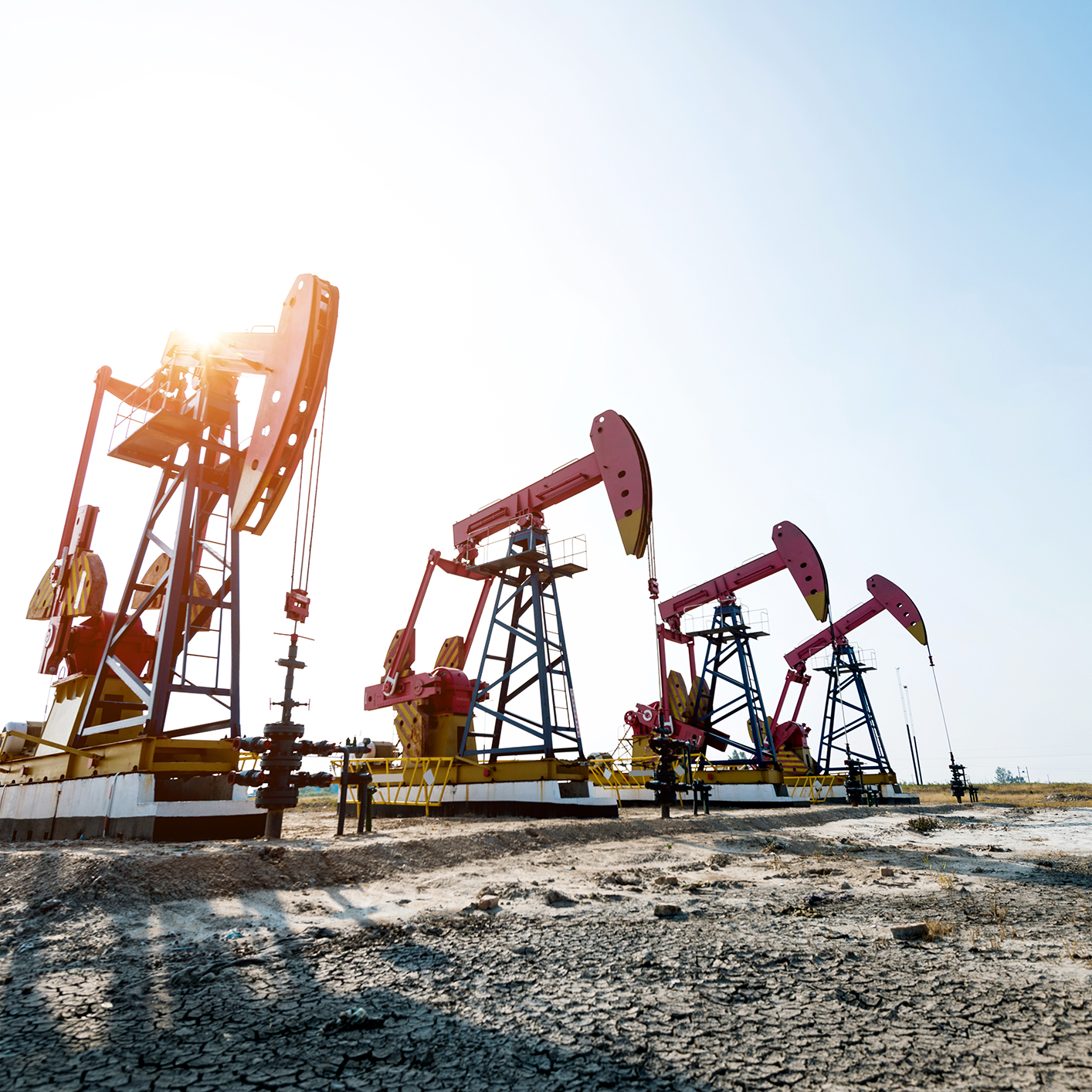 Several oil pumpjacks operate in a dry, barren landscape under a bright sky, much like lawyers in Chicago tirelessly working to extract the best outcomes for clients.