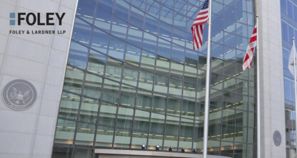 Exterior de un moderno edificio de oficinas con grandes ventanales, dos banderas estadounidenses y un letrero que reza «Foley &amp; Lardner LLP» en la parte superior izquierda, en el que se destaca un destacado bufete de abogados conocido por su apoyo en litigios y su especialización en derecho de la propiedad intelectual.