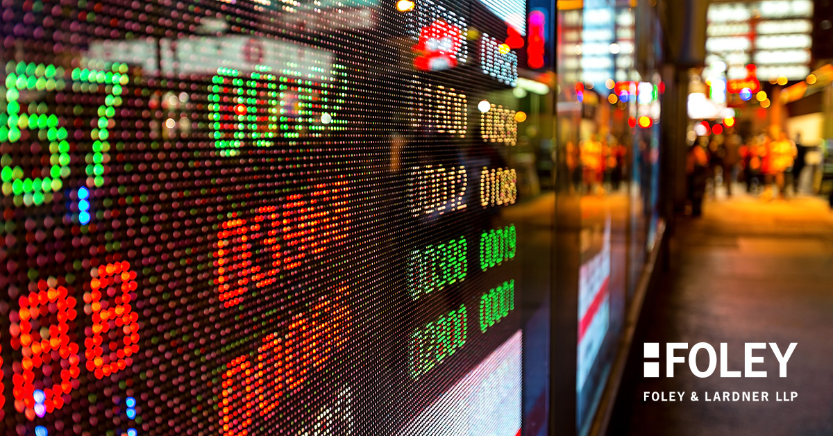Digital stock ticker displays numbers and prices in bright colors on a city street, with the Foley & Lardner LLP corporate law office logo visible in the lower right corner.