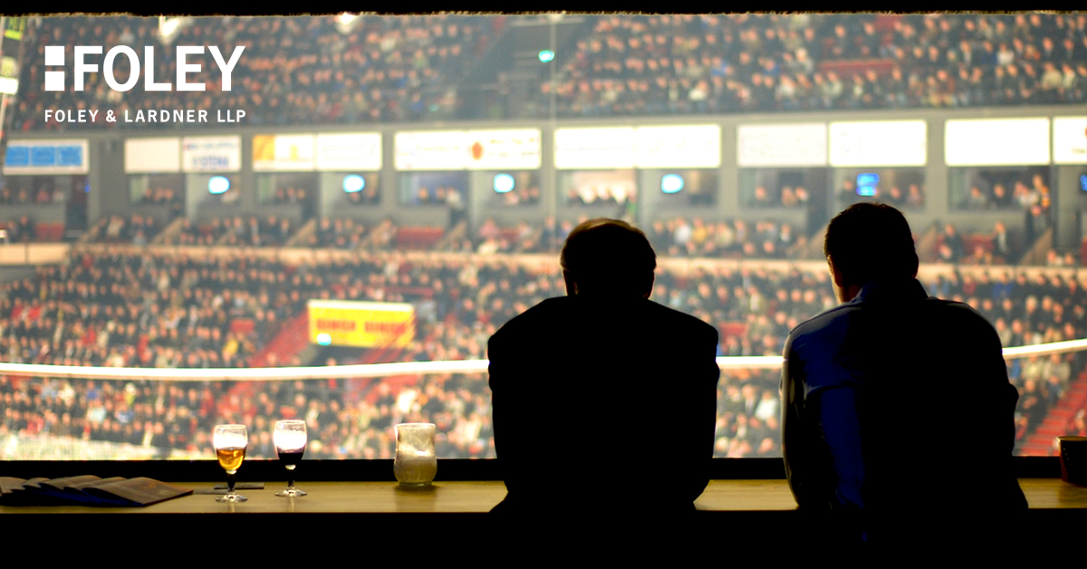 Two people sit at a bar overlooking a crowded arena with drinks on the counter; the Foley & Lardner LLP logo—known for expertise in intellectual property law—is visible in the upper left corner.