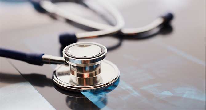 A stethoscope rests on top of an X-ray film, both placed on a flat surface in a corporate law office.