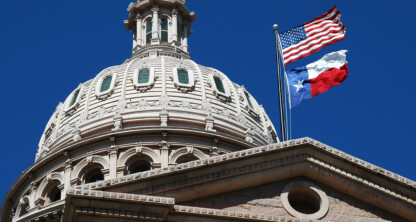The dome of a government building with American and Texas flags flying, set against a clear blue sky, evokes the dignified presence of prominent law offices handling important matters of justice and governance.