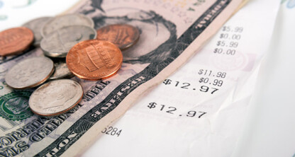 A close-up of U.S. coins and a ten-dollar bill placed on a printed receipt for $12.97, symbolizing everyday transactions—an image often used by law offices or Chicago lawyers to illustrate litigation support in financial matters.