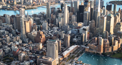 Aerial view of Lower Manhattan, New York City, showcasing tall skyscrapers, bustling waterfront, and surrounding rivers—home to many leading corporate law offices under a partly cloudy sky.