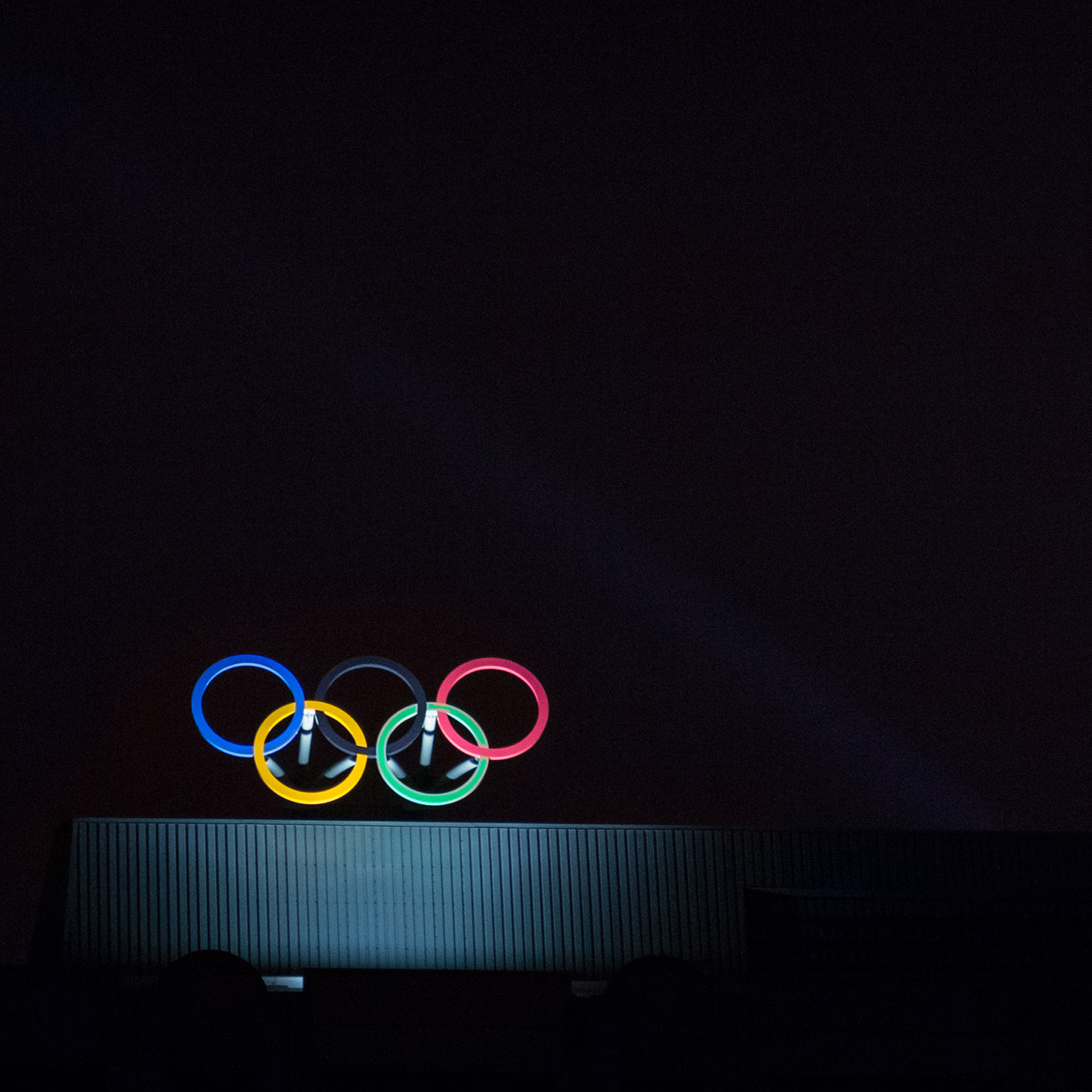 Illuminated Olympic rings atop a dark building against a black night sky, reminiscent of the impressive skylines that house prominent Chicago lawyers and corporate law office headquarters.