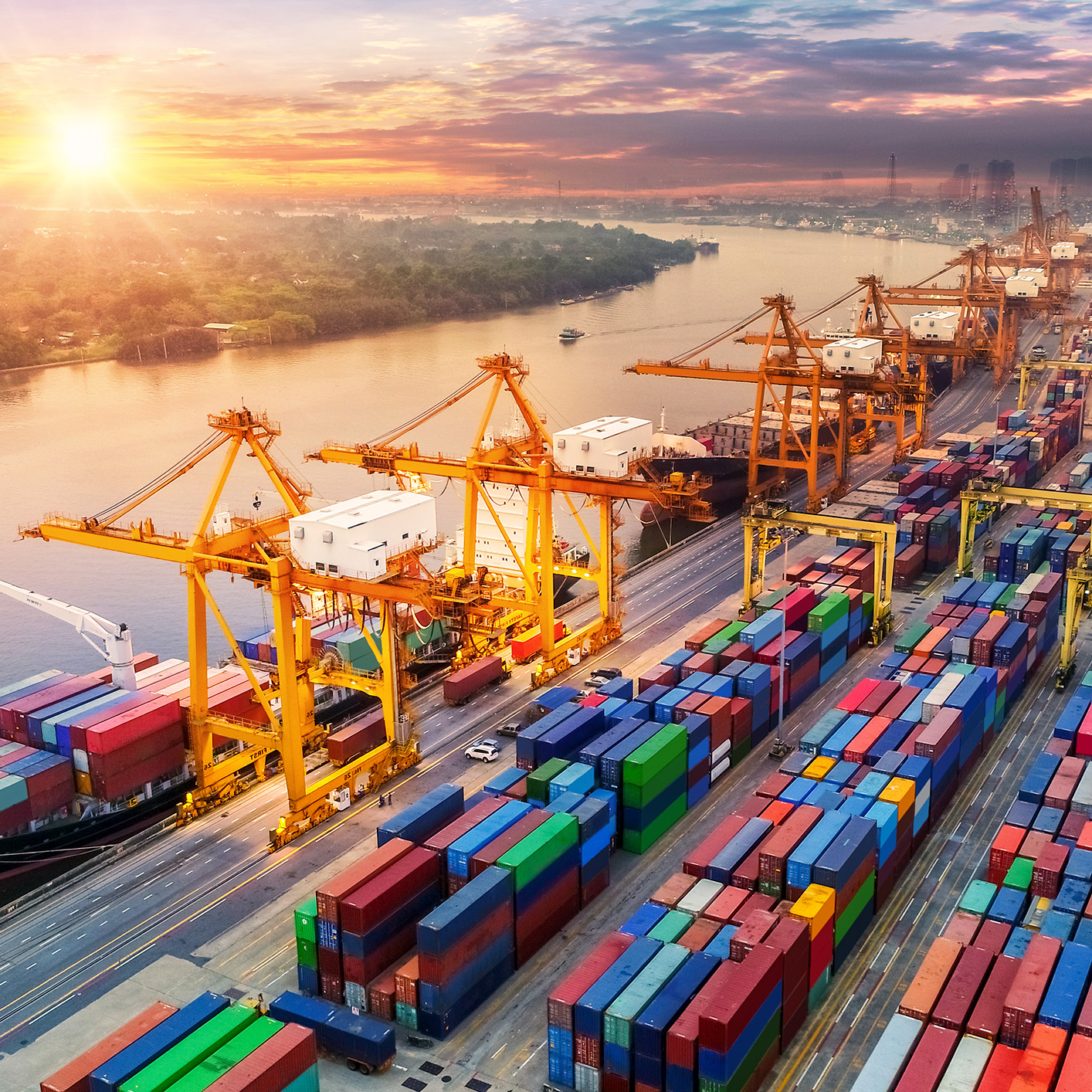 A busy container port with cranes unloading cargo from ships, colorful shipping containers stacked, and a river with the sun setting in the background—an efficient scene not unlike bustling Chicago law offices managing complex logistics.
