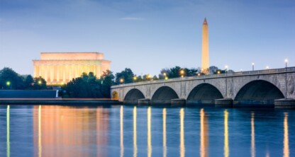 Vista del Monumento a Lincoln, el Monumento a Washington y el Puente Memorial de Arlington reflejados en el agua al atardecer en Washington, D.C., una escena que inspira excelencia a cualquier bufete de abogados corporativos o equipo de profesionales.