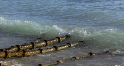 Varias tuberías metálicas oxidadas se adentran desde la orilla en las aguas cristalinas y poco profundas del océano, mientras pequeñas olas rompen a su alrededor, de forma muy similar a como los abogados de Chicago se abren paso por las complejas aguas jurídicas en defensa de sus clientes.