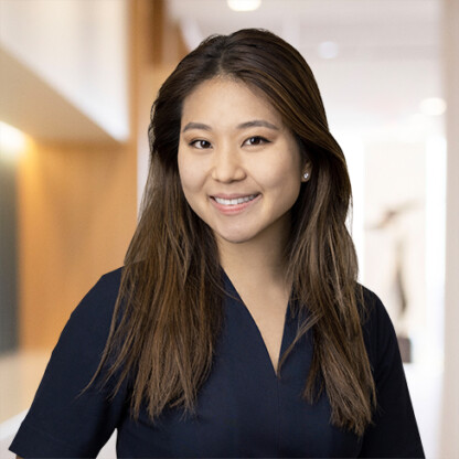 A woman with long brown hair wearing a navy blouse smiles at the camera in a well-lit, modern corporate law office, capturing the professional atmosphere often found among lawyers in Chicago.