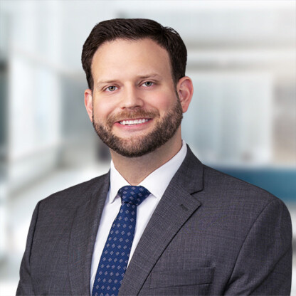 A man in a suit and tie smiles at the camera in a professional indoor setting, likely one of the law offices of leading Chicago lawyers, with a blurred background.