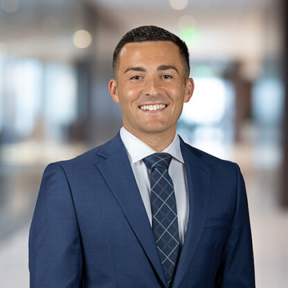 A man in a blue suit and patterned tie smiles at the camera in a modern law office setting, highlighting the professionalism of lawyers in Chicago.