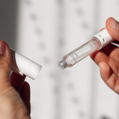 A person holds an insulin pen in one hand and removes the cap with the other hand, illustrating precision and care much like chicago lawyers handle complex litigation support.