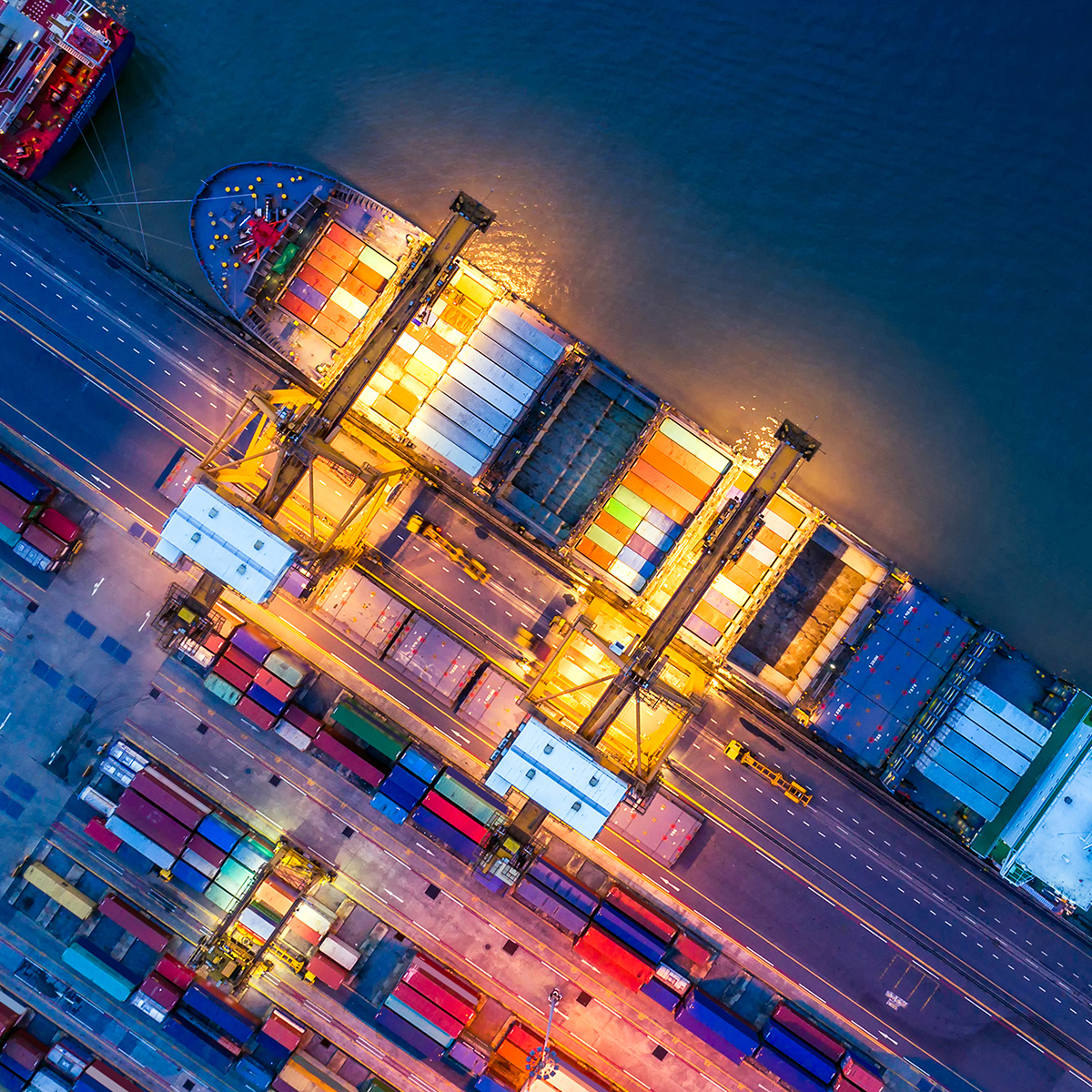 Aerial view of a cargo ship docked at a port, with cranes loading or unloading colorful shipping containers—a view reminiscent of the organization found in top law offices or among skilled lawyers in Chicago.