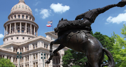 Una estatua ecuestre de bronce se alza frente al Capitolio del Estado de Texas, con las banderas de Texas y de Estados Unidos ondeando sobre la cúpula bajo un cielo azul: una escena admirada por los abogados de Chicago por su importancia histórica.