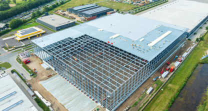 A building under construction with many buildings and a river.