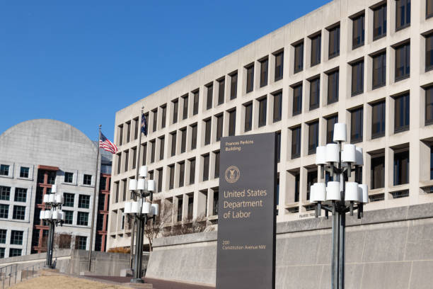 United States Department of Labor building with signage, American flags, and modern architecture on a clear day.