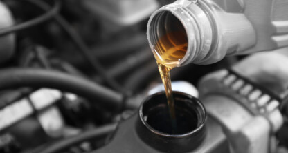 Engine oil being poured into a car engine during maintenance.