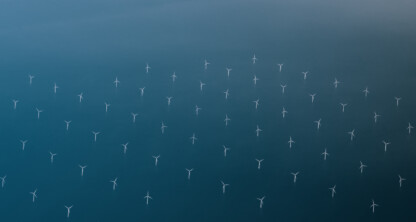 Aerial view of numerous wind turbines in a cloudy sky.